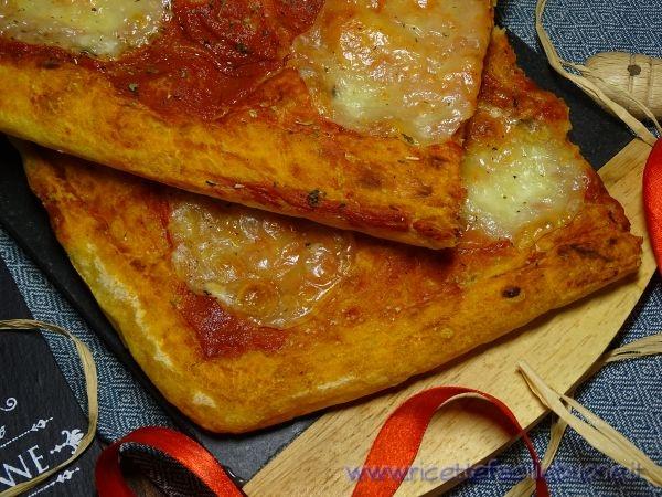 Pizza Margherita pronta da gustare tagliata in tranci e messa su tagliere di legno